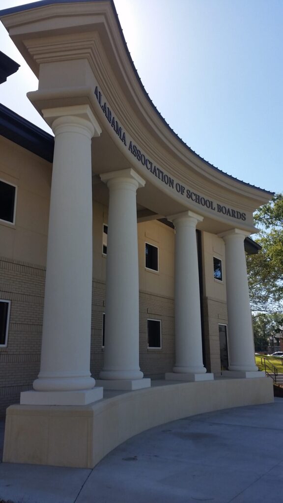 Front entrance of the Alabama Association of School Boards building with four large white columns and curved roof.