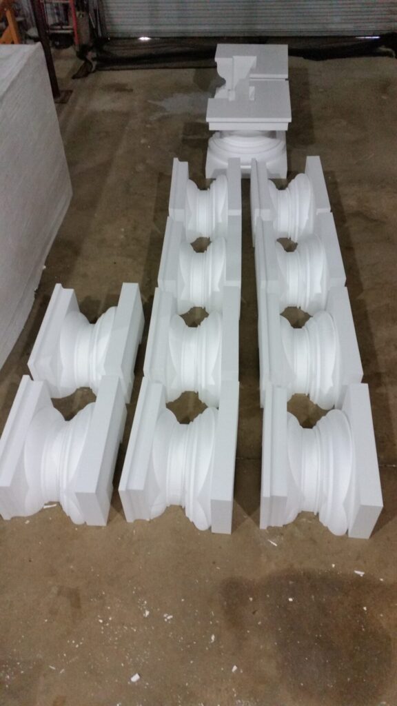 Six pairs of white architectural column bases arranged on a concrete floor in three rows.